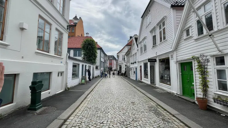 A quiet cobbled Bergen street lined with white wooden houses and small shopfronts