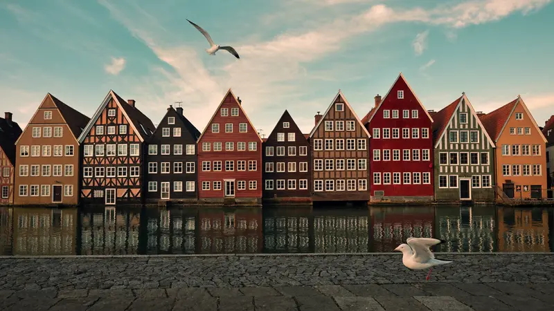 Colourful wooden Bryggen wharf houses reflected in still Bergen harbour water