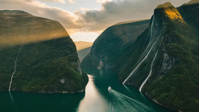 Aerial view of Geirangerfjord winding between mountain walls at golden hour