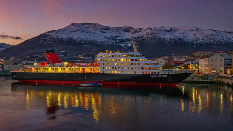 Coastal ferry ship docked at a small Norwegian harbour town at dusk