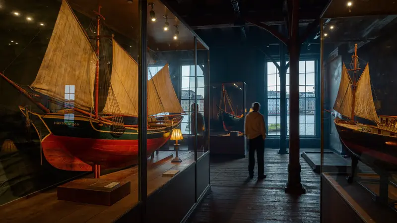 Warmly lit historic maritime museum interior in Bergen with wooden ship models