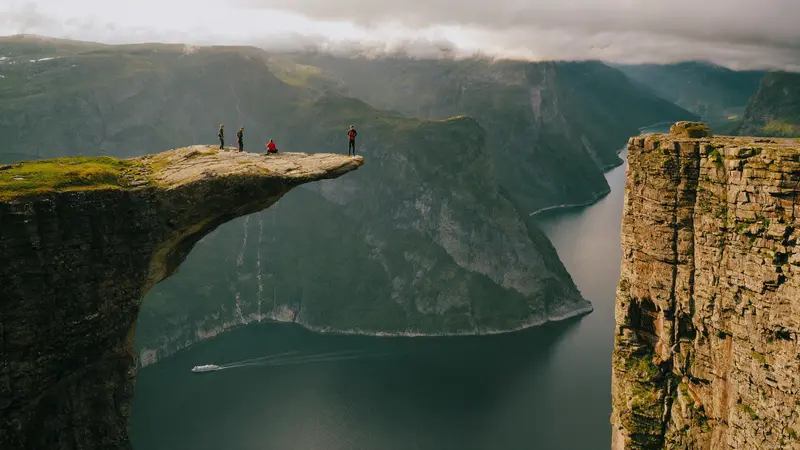 Hikers on the flat cliff top of Preikestolen high above the Lysefjord